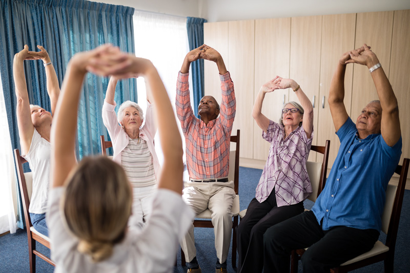 Kamloops independent or assisted living community residents doing chair exercises and stretches