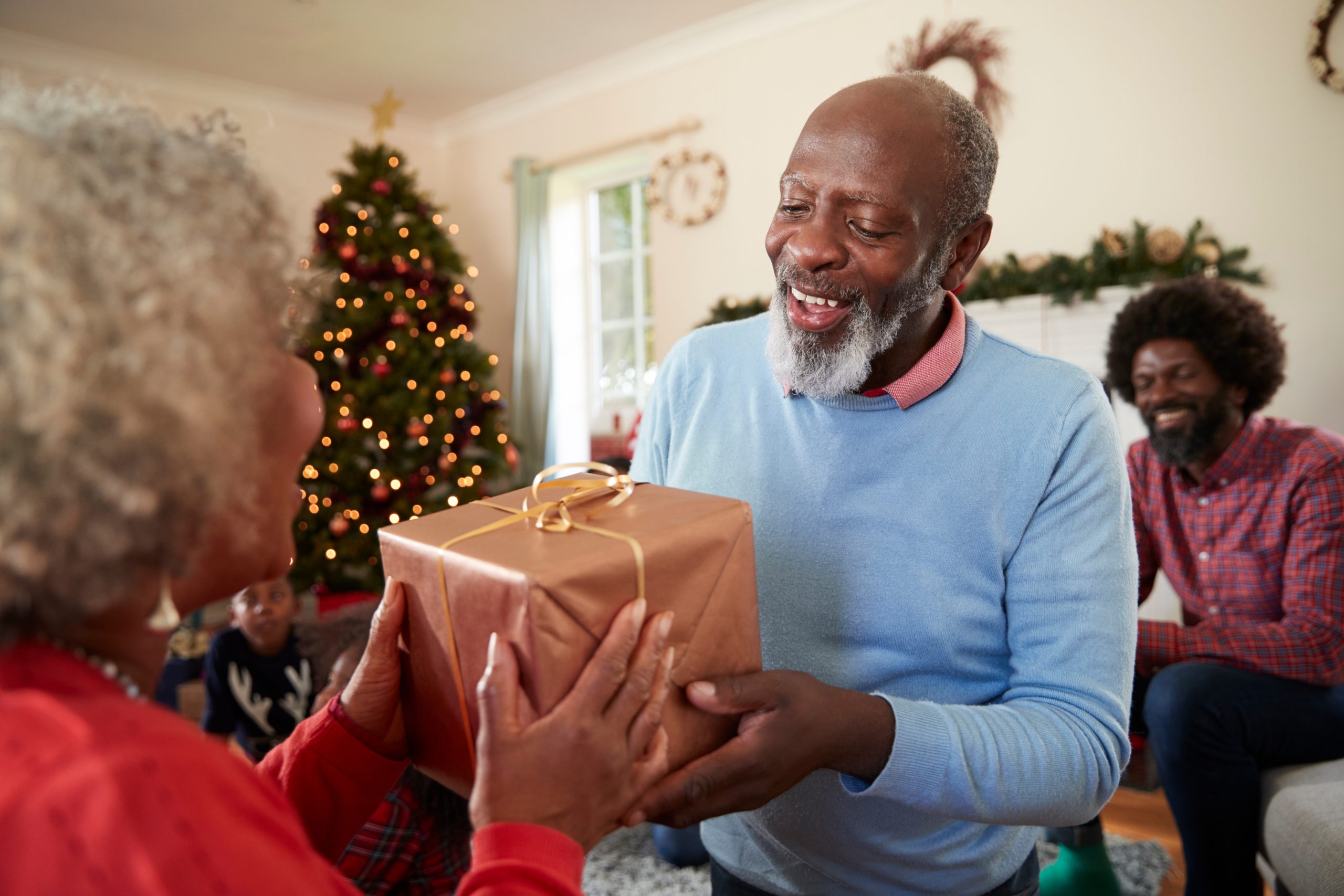 Senior Couple Exchanging Gifts As They Celebrate Christmas At Home With Family