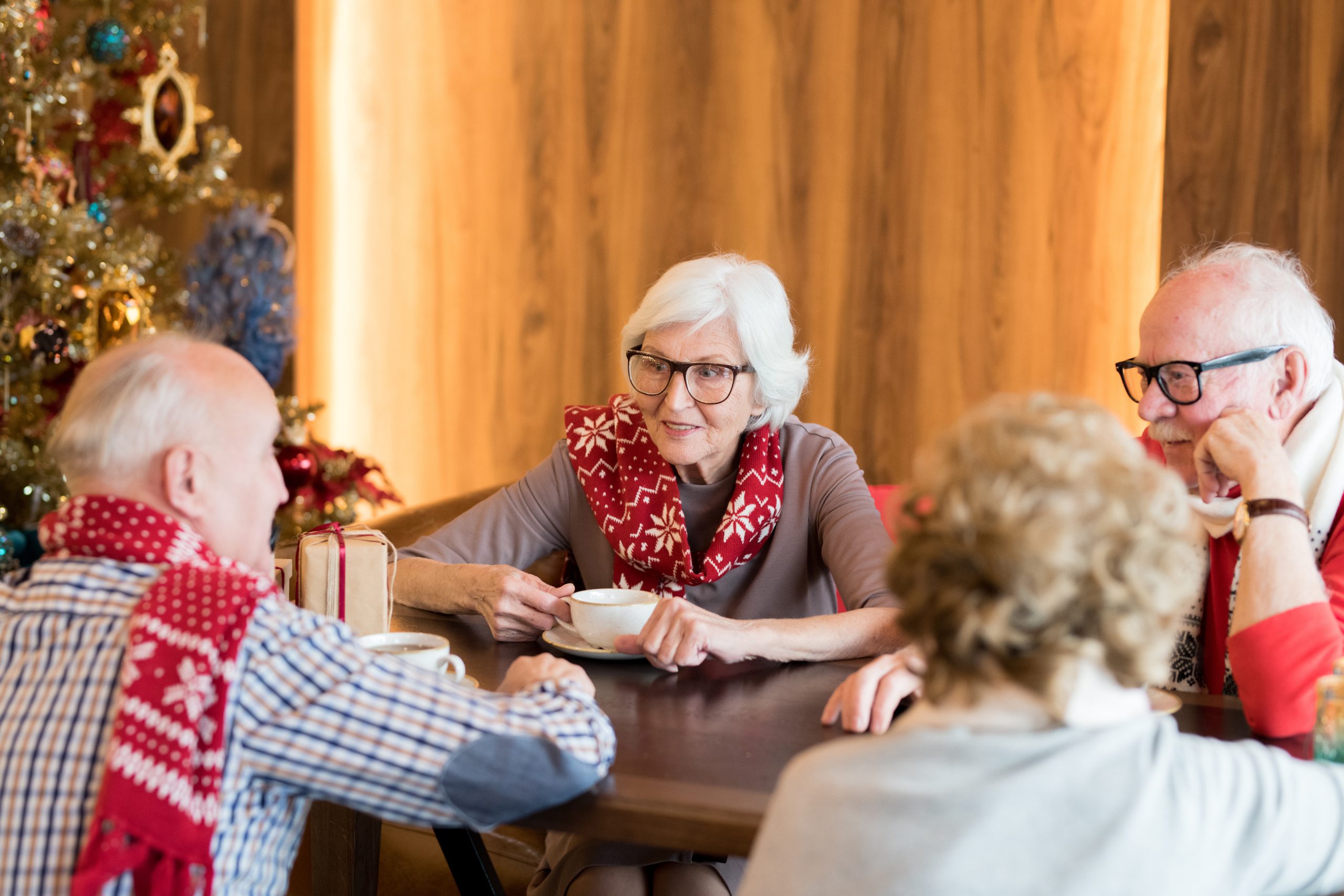 Positive elderly friends drinking coffee at Christmas eve