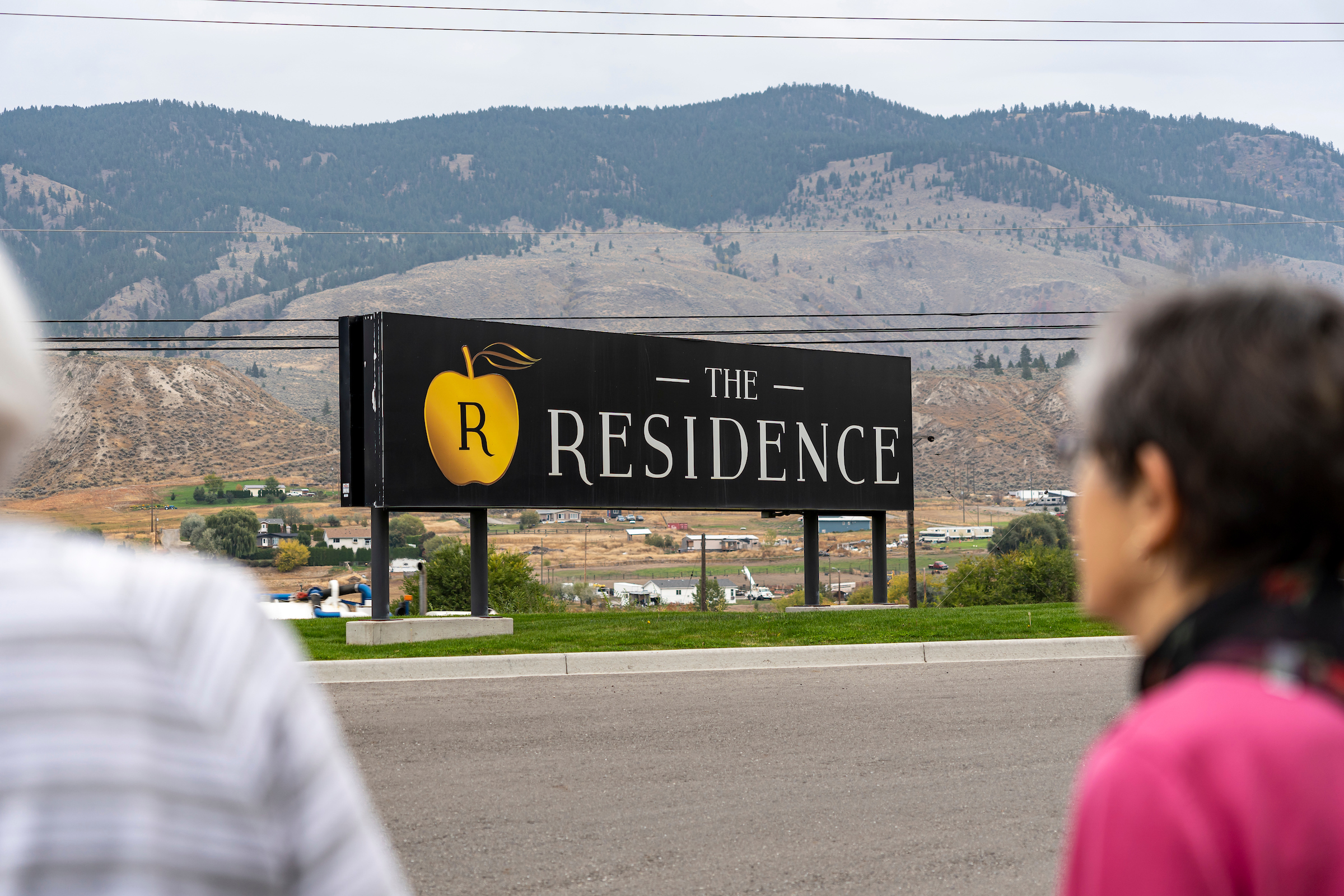 two seniors looking at a sign for the residence